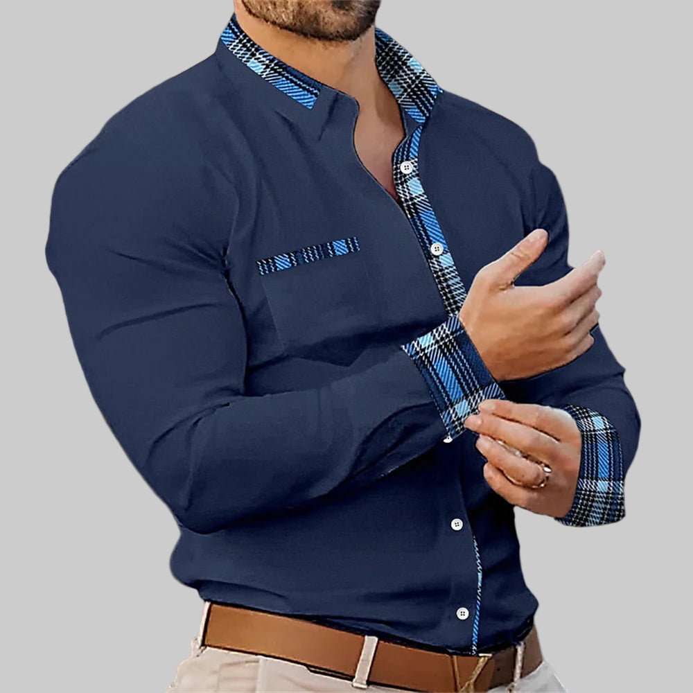 Man wearing a navy blue shirt with plaid accents in an indoor setting