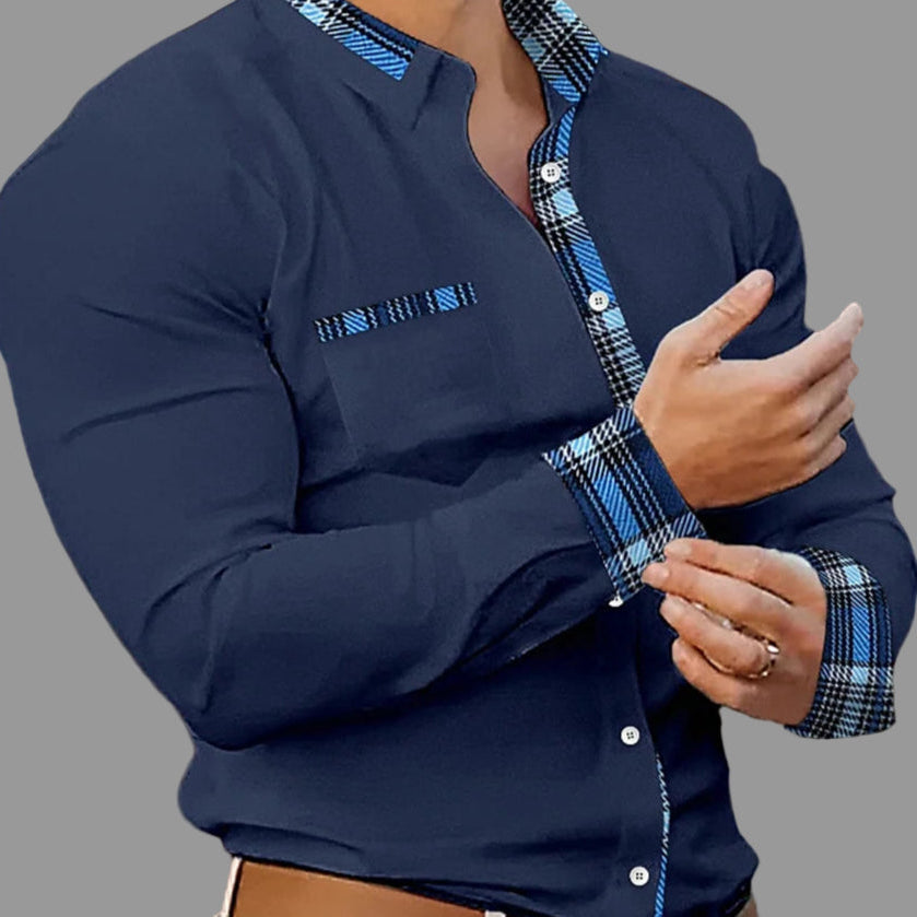Man wearing a navy blue shirt with plaid accents in an indoor setting