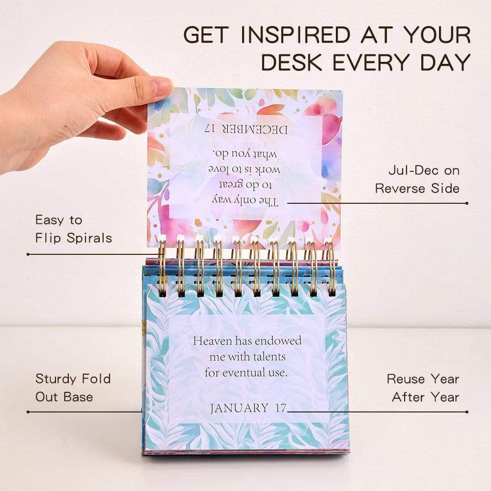 Small spiral-bound planner with colorful design held by a hand, on a light background.