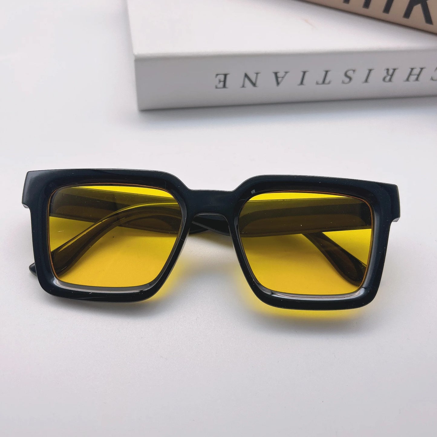 Sunglasses with yellow lenses and black frames on a gray background