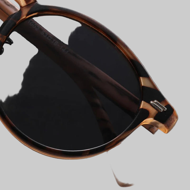 Sunglasses with brown frame and black lenses on a light gray background