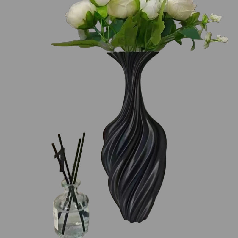 Black textured vase with white flowers on a surface with decorative items.