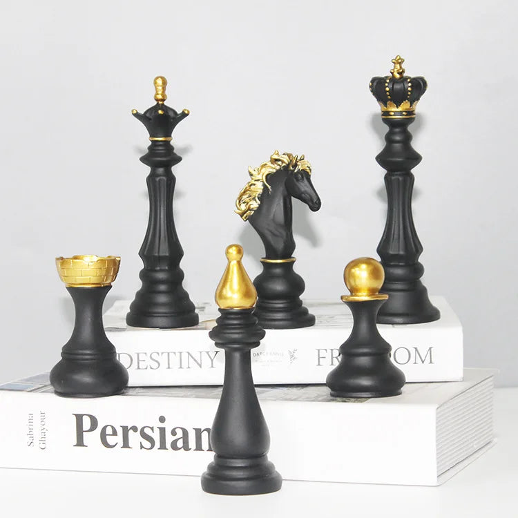 Black and gold chess pieces on a white surface with books in the background