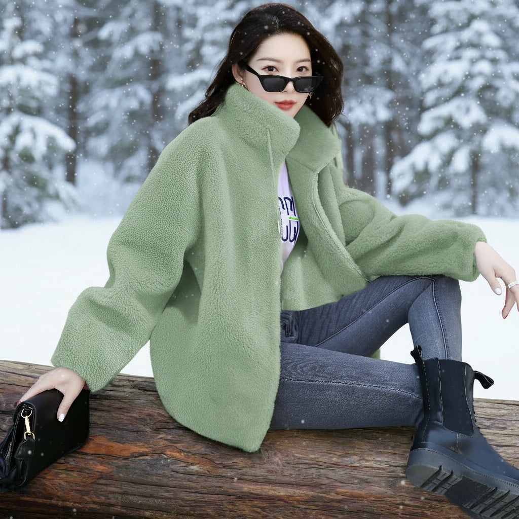 Woman wearing a green sweater and sunglasses sitting on a bench.