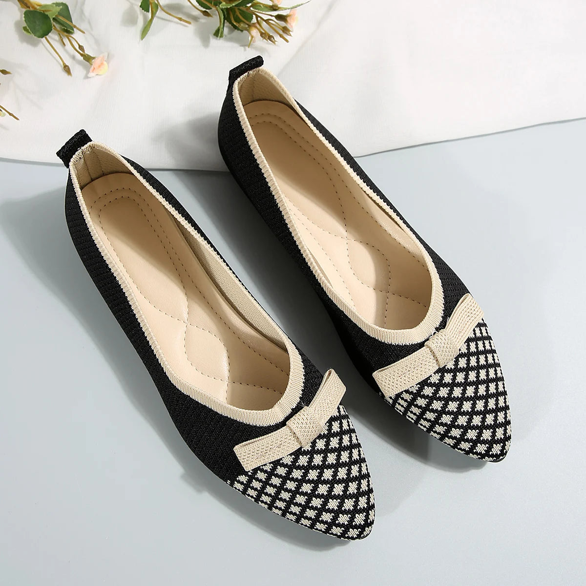 Black and white checkered shoes with a bow on a light gray background