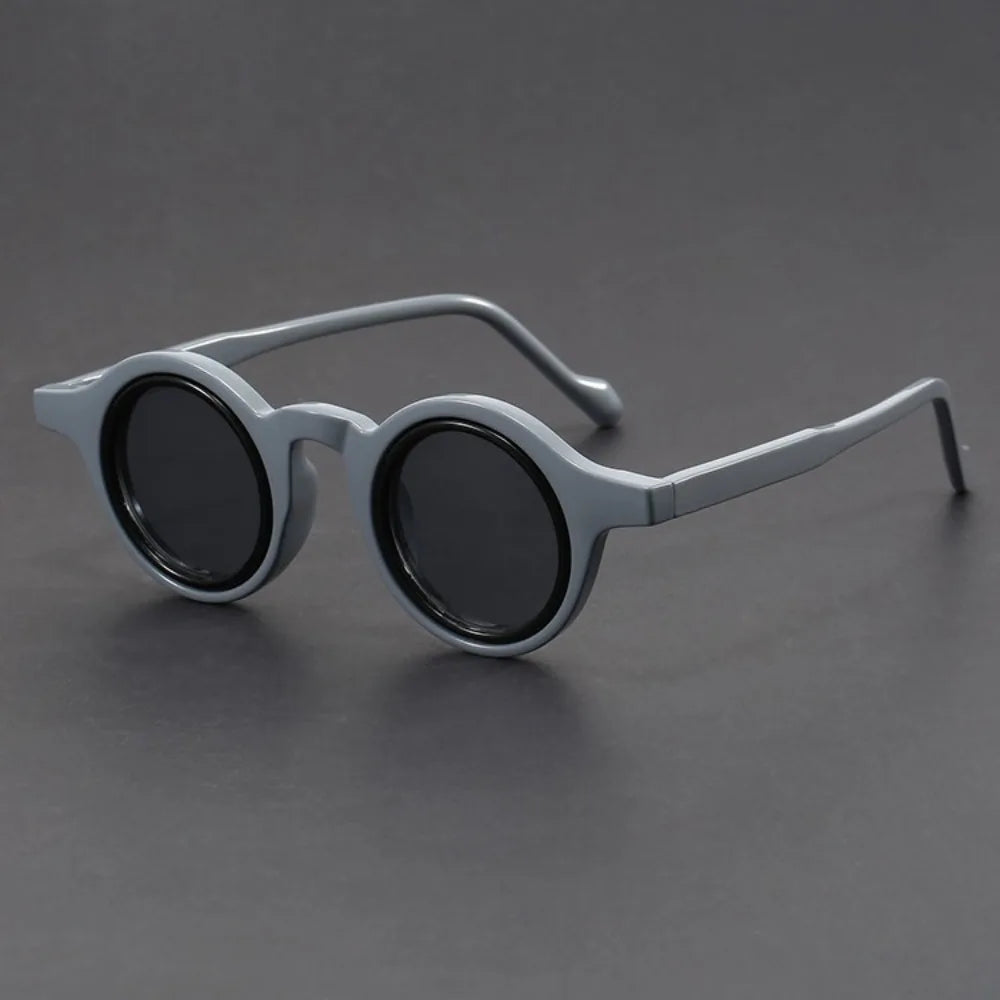 Round sunglasses with dark lenses and light gray frame on a gray background