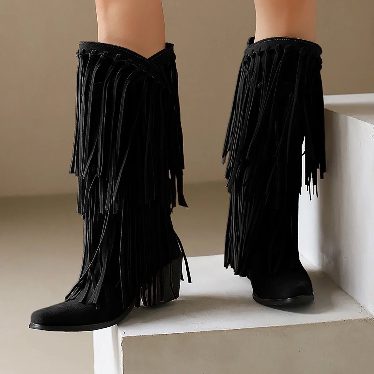 Black fringed boots on a neutral background
