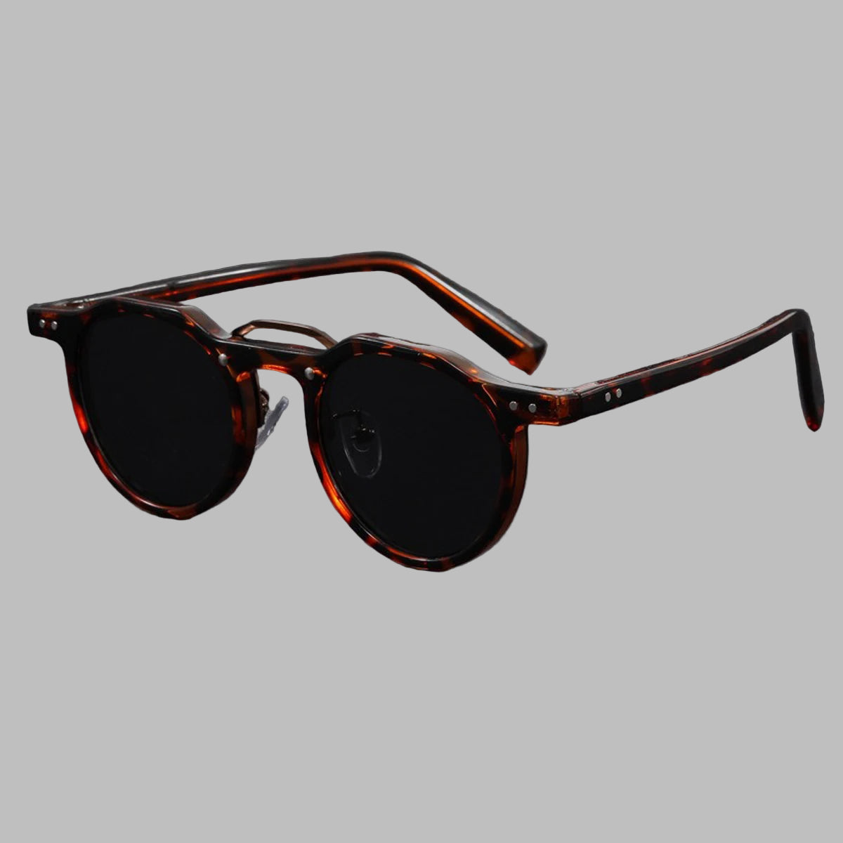 Sunglasses with tortoiseshell frame and dark lenses on a gray background