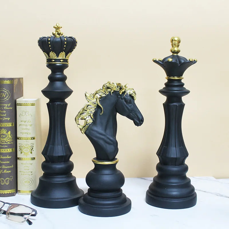 Black and gold chess pieces including a king, queen, and horse on a white surface with books in the background.