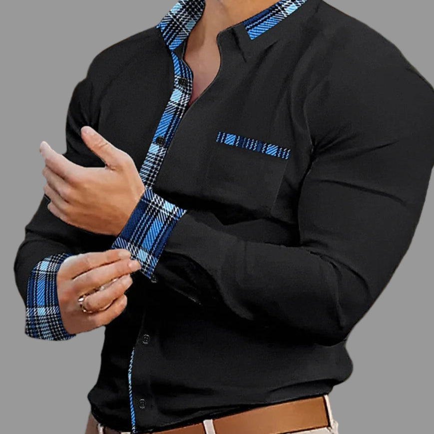 Man wearing a black shirt with blue plaid accents in an indoor setting