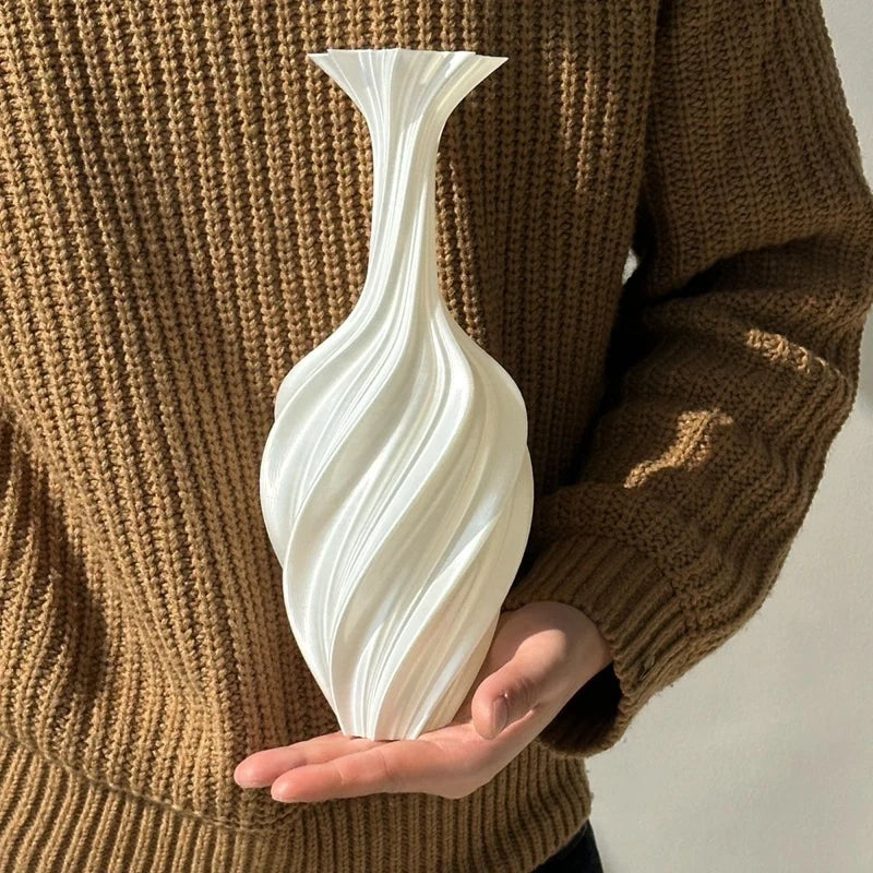 Person holding a white swirled vase against a brown sweater background