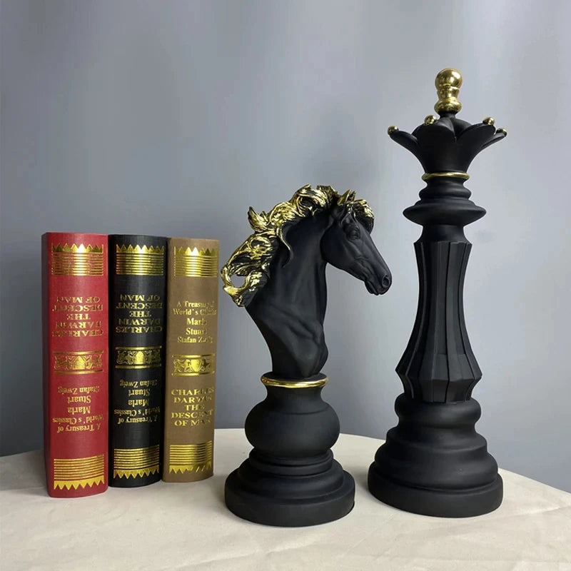Black chess pieces with gold accents on a surface with books in the background