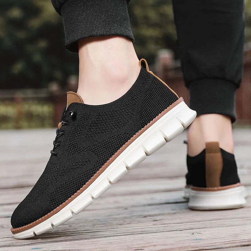 Black knit shoes with white soles worn by a person on a wooden floor.
