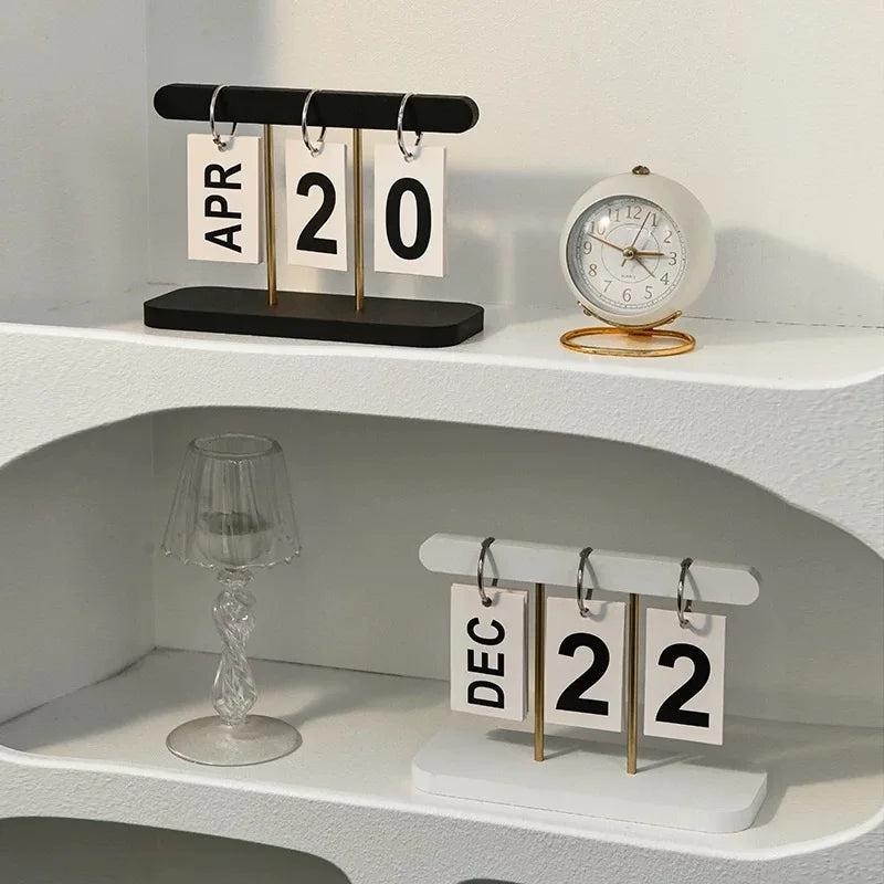 Two calendar sets on a shelf with a clock and decorative items.