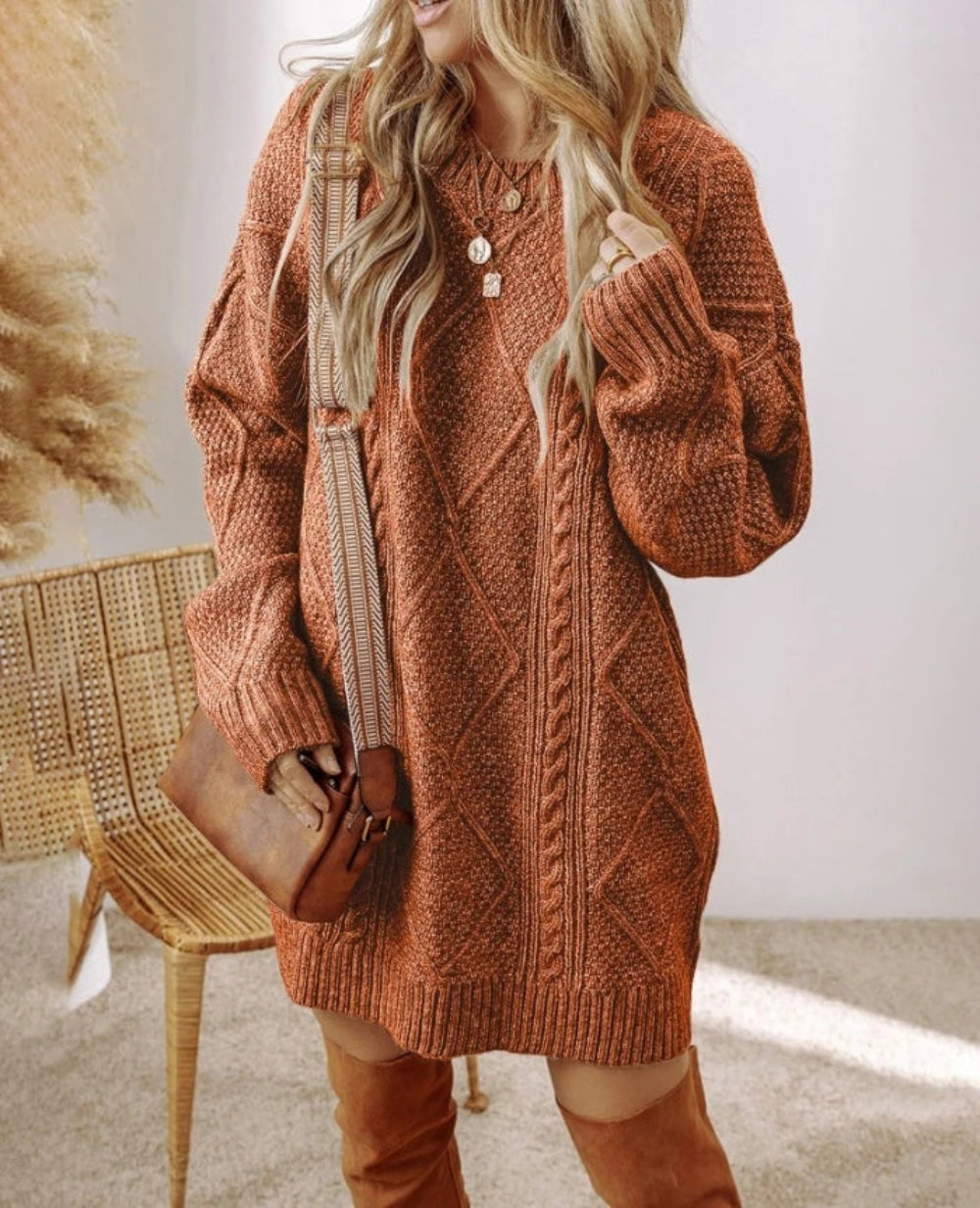 Person wearing a brown knitted dress with a textured pattern, holding a brown bag indoors.