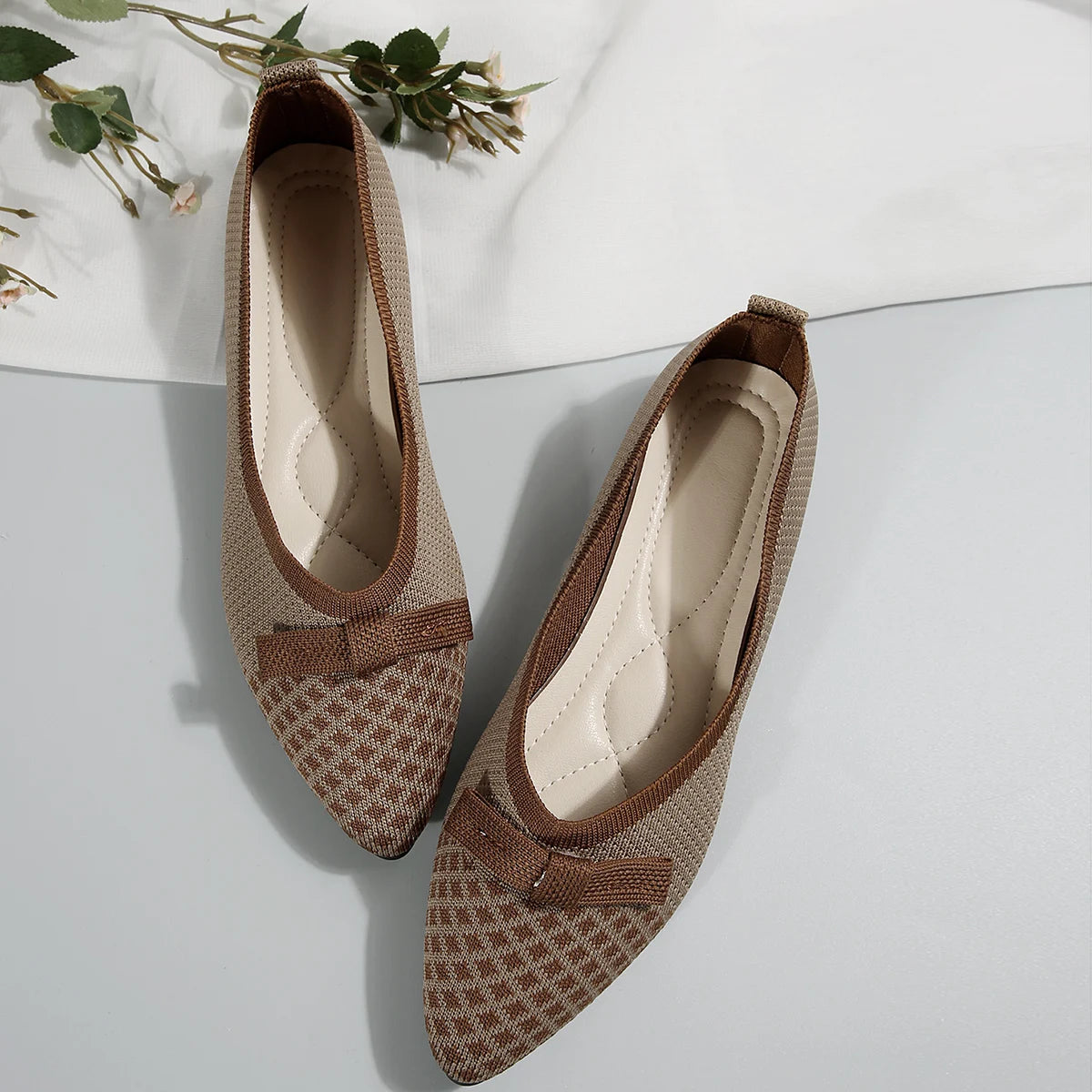 Pair of brown patterned shoes with a bow on a white background
