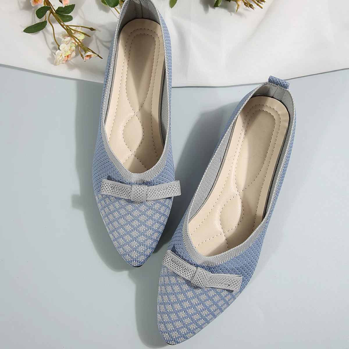 Pair of blue patterned shoes with a bow on a light gray background