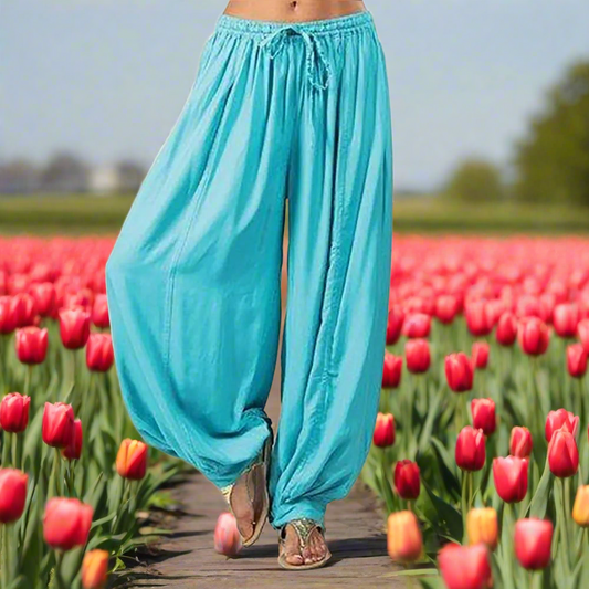 Person wearing turquoise pants standing in a tulip field