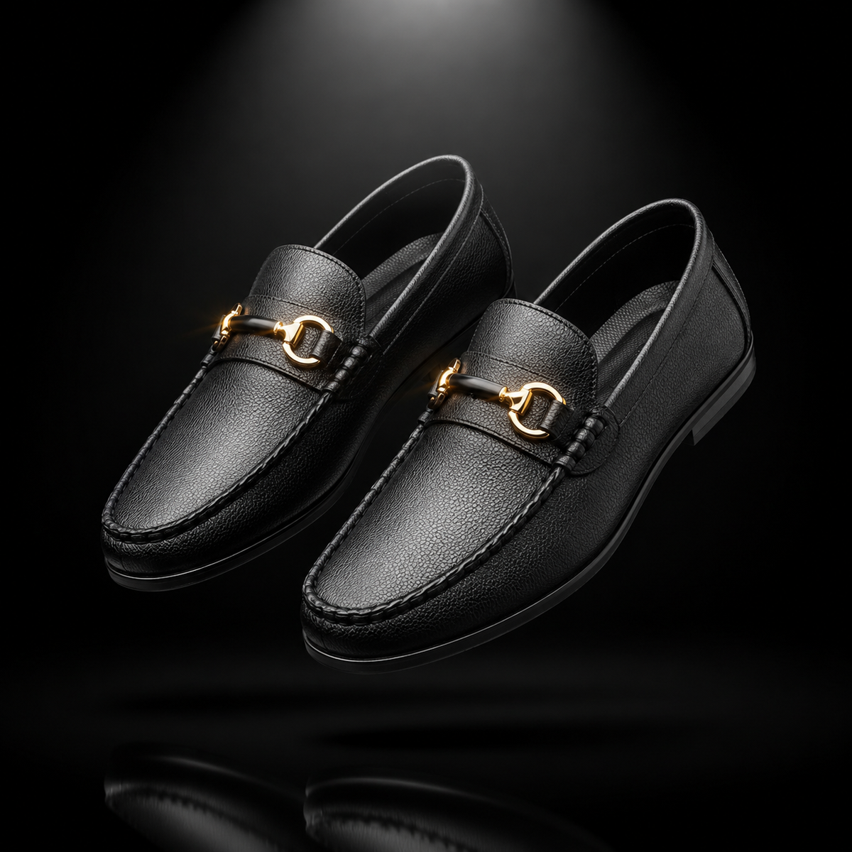 A pair of black leather penny loafers with gold-tone horsebit hardware, shown floating against a dark black background with a subtle reflection below.