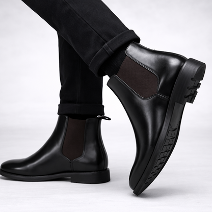 Black leather boots worn with black pants on a white background