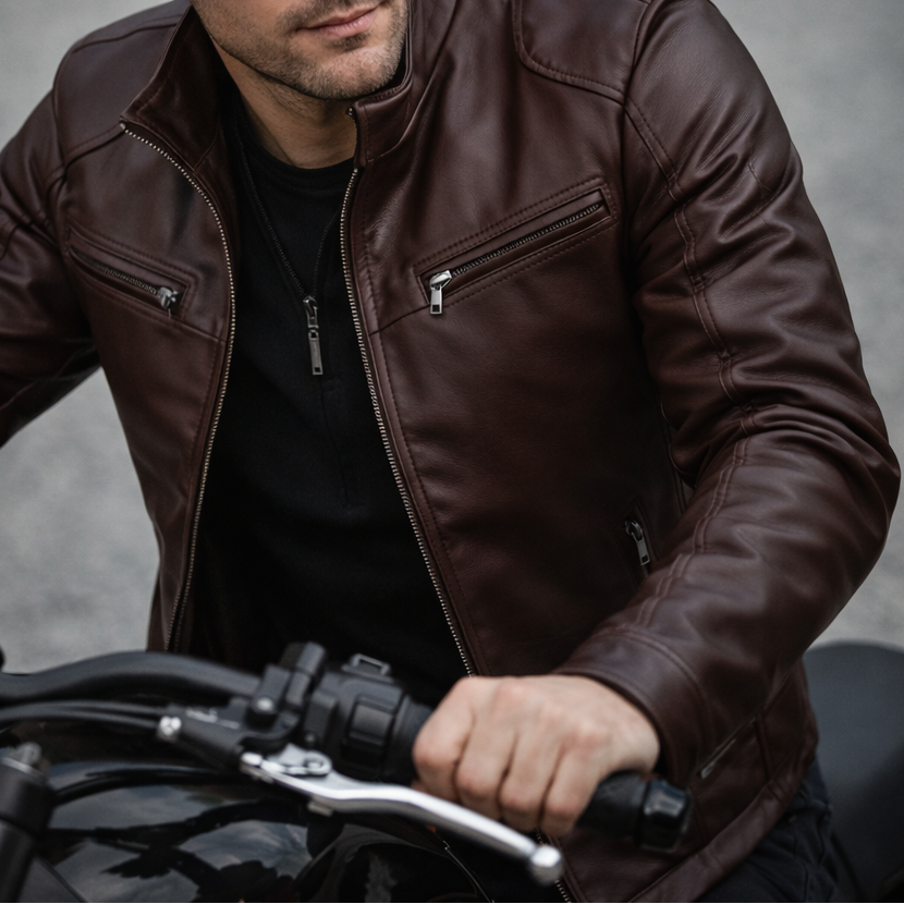 Man wearing a brown leather jacket sitting on a motorcycle.