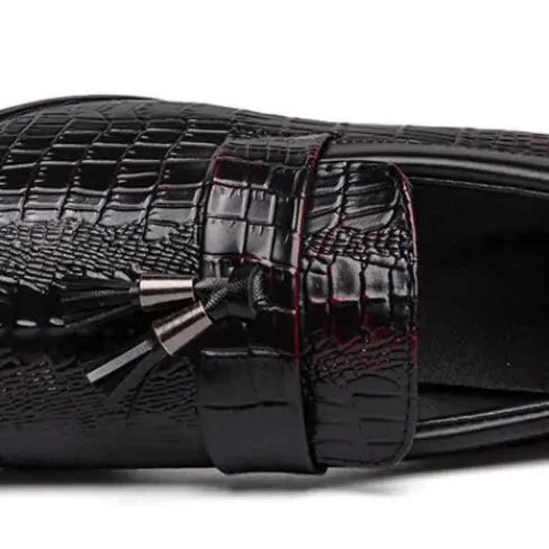 Black crocodile-patterned slide sandal with a decorative bow on a white background