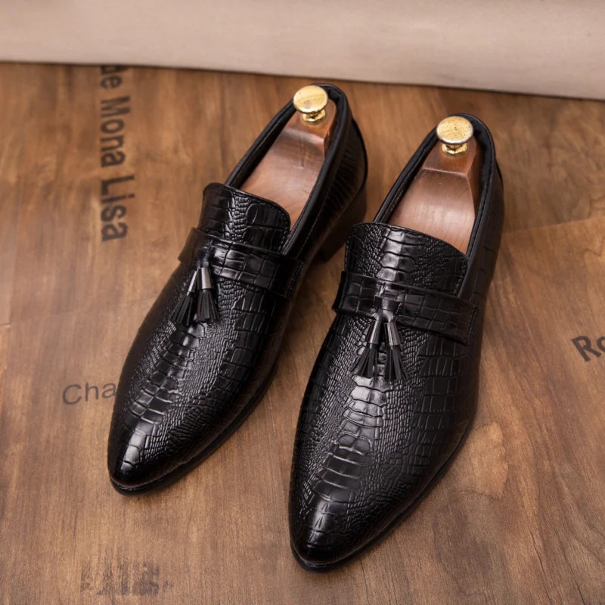 Black leather shoes with tassels on a wooden surface