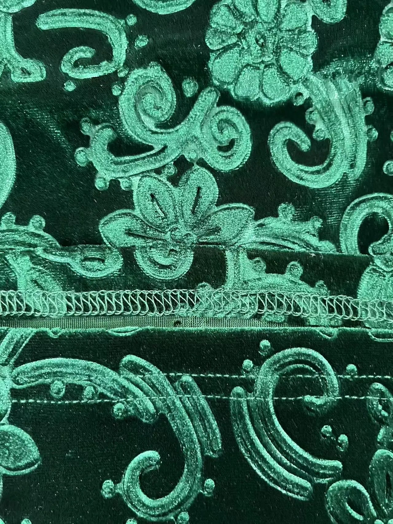 Close-up of green embroidered fabric with floral patterns on a black background