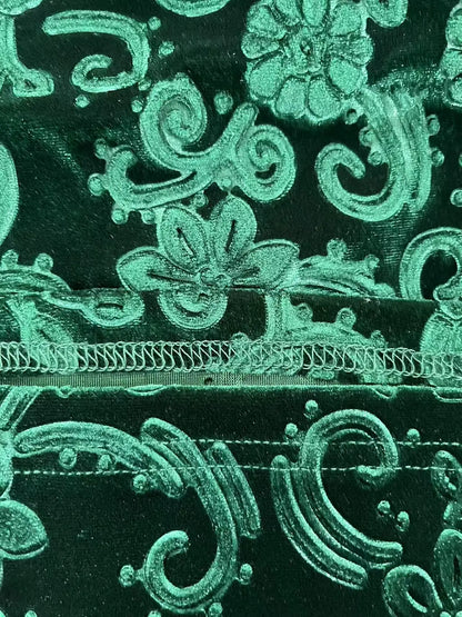 Close-up of green embroidered fabric with floral patterns on a black background