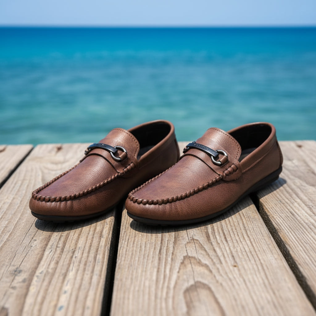 Brown loafers displayed on a textured surface with a blurred background.