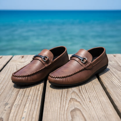 Brown loafers displayed on a textured surface with a blurred background.