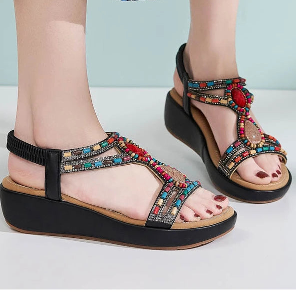 Colorful sandals with decorative straps worn by a person on a light background