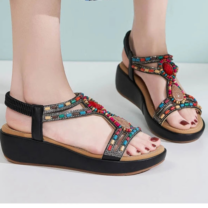 Colorful sandals with decorative straps worn by a person on a light background