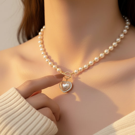 Pearl necklace with a heart-shaped pendant worn by a person in a white sweater.