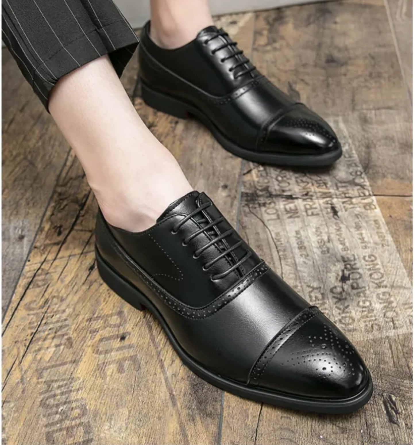 Black dress shoes worn on a wooden floor
