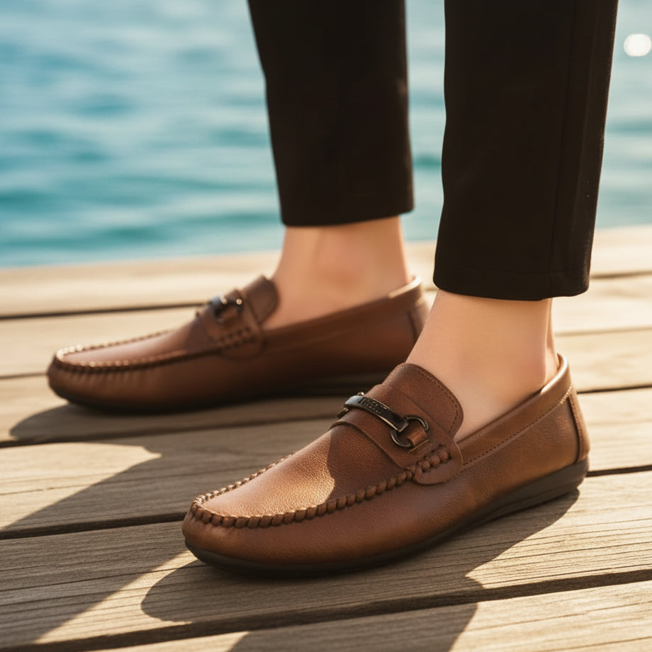 Brown leather loafers worn indoors on a carpeted floor.