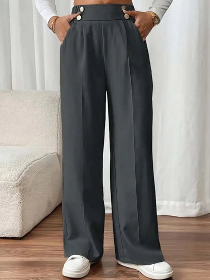 Person wearing dark gray wide-leg pants with a white background