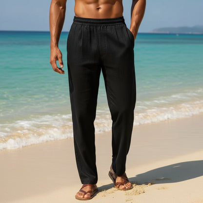 Person wearing black pants standing on a boat with ocean and mountains in the background