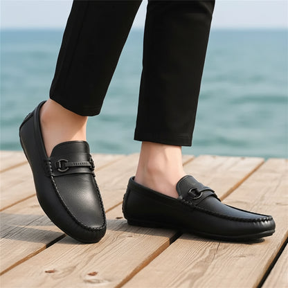 Black leather loafers worn with black pants on a neutral background