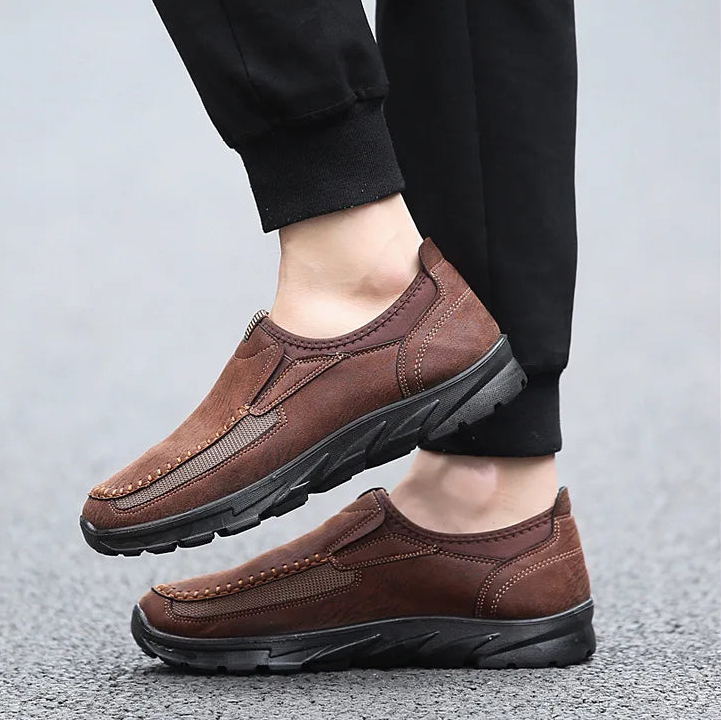 Brown leather shoes worn with black pants on a light gray background