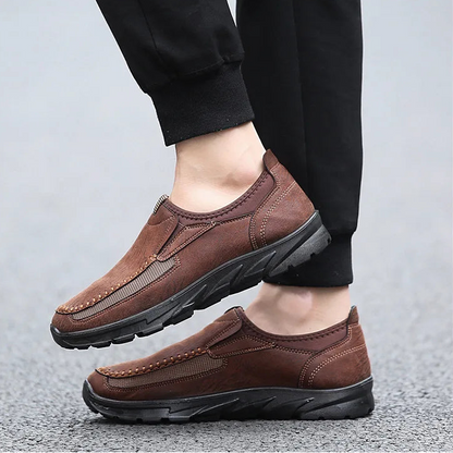 Brown leather shoes worn with black pants on a light gray background