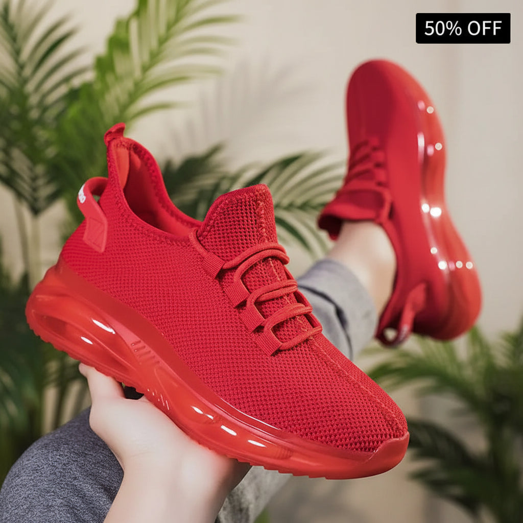 Red athletic shoes held by a person with a blurred background