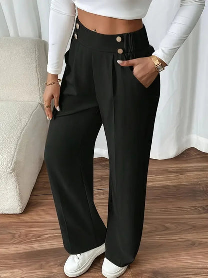 Person wearing black wide-leg pants with a white top and white sneakers on a wooden floor.