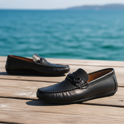 Black leather loafers worn with black pants on a gray floor.