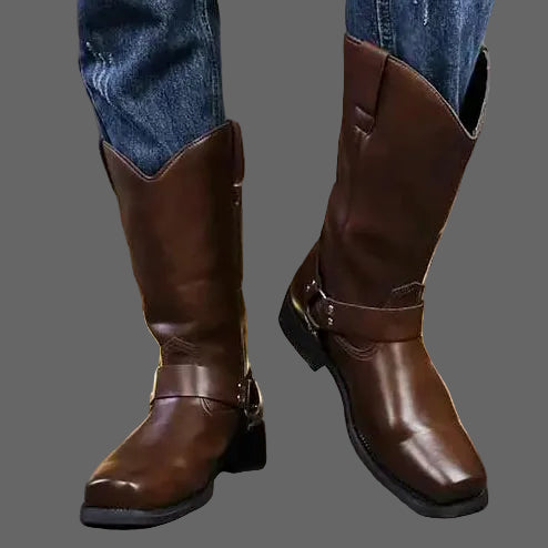 Brown leather boots worn with blue jeans against a neutral background