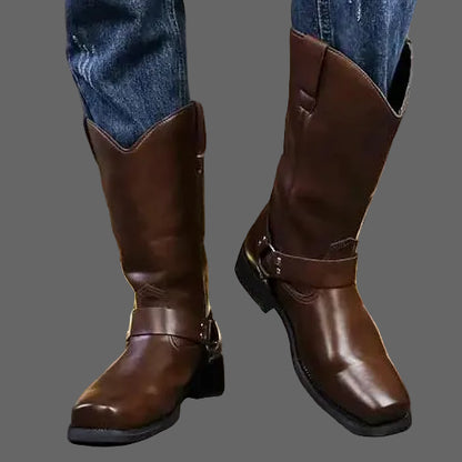 Brown leather boots worn with blue jeans against a neutral background