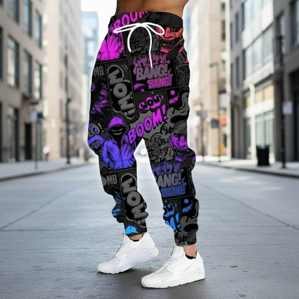 Black jogger pants with colorful text and graphics worn by a person on a gray background