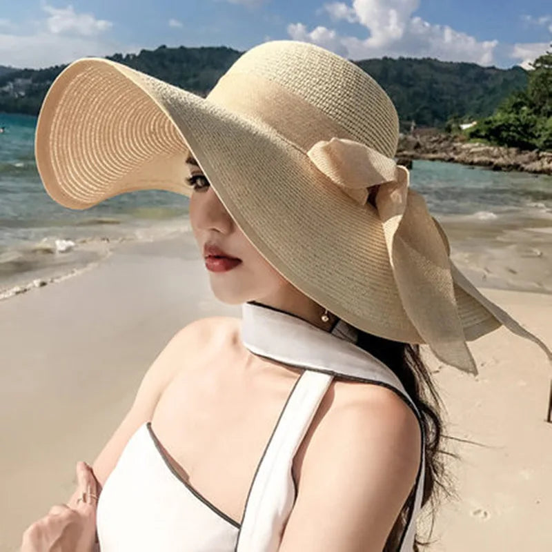 Woman wearing a large beige hat with a bow on a beach
