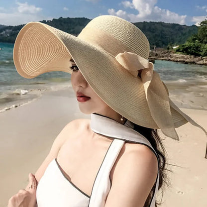 Woman wearing a large beige hat with a bow on a beach