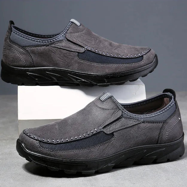 Two pairs of men's loafers, one gray and one brown, on a gray background.